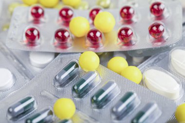 Multi-colored pills and capsules lie on the table. Scattered dru