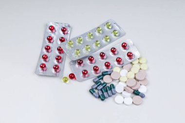 Multi-colored pills and capsules lie on the table. Scattered dru