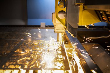 Otomatik programlanmış makine. Endüstriyel lazer makinesi çelik levha parçalarını kesiyor. Sıcaklık. Fabrikadaki üretim makinesinin çalışması sırasında kıvılcımlar.
