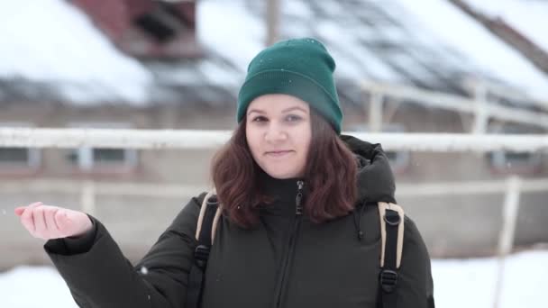 Eine junge Frau fängt Schneeflocken mit der Hand im Schneefall. — Stockvideo