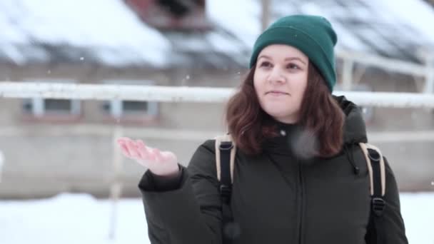 Eine junge Frau fängt Schneeflocken mit der Hand im Schneefall. — Stockvideo