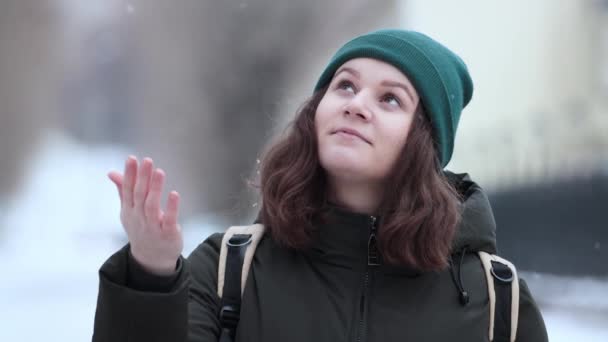 Una giovane donna cattura i fiocchi di neve con la mano in una nevicata . — Video Stock