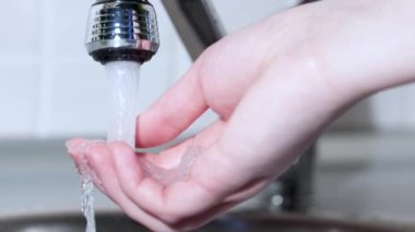 Bir adam mutfakta musluğu açar ve elini yıkar. Musluğu kapatıyorum. Yavaş çekim.