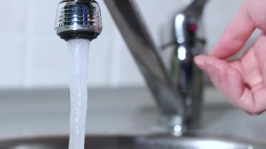 Bir adam mutfakta musluğu açar ve elini yıkar. Musluğu kapatıyorum. Yavaş çekim.