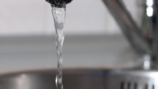 A víz a csapból a mosogatóba folyik. Kinyitja és lezárja a csapot. Lassított felvételen. — Stock videók