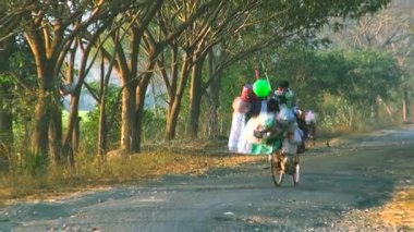Satıcı adam balonlar ve el sanatları, yol kenarında taşıyan ile bisiklet üzerinde.
