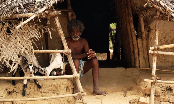 NANNILAM, INDIA - 11 MAY 2016: Indian senior man looking at the camera and sitting on poor village house exterior — Stock Photo, Image