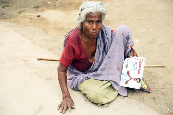 NANNILAM, INDIA 11 MAJ 2016: Indisk senior kvinde sidder på en travl vej - Stock-foto
