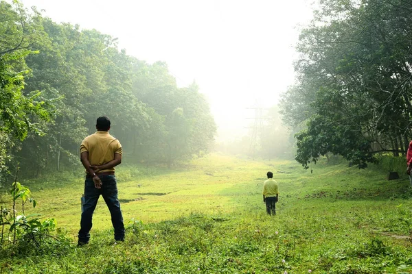 Junger Mann posiert und dreht sich vor laufender Kamera um. mit einer wunderschönen grünen Parklandschaft im Hintergrund. — Stockfoto