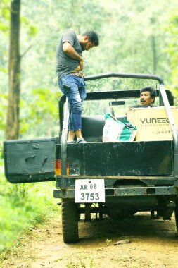 Kodaikanal, Hindistan - 29 Haziran 2015: Jeep üzerinde orman yolu, bir arabada oturan kamera bakarak adam