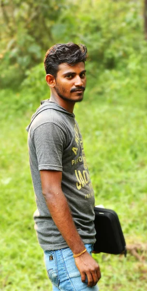 KODAIKANAL, ÍNDIA - 29 de junho de 2015: Um homem olhando para a câmera com a mão do laptop segurando — Fotografia de Stock