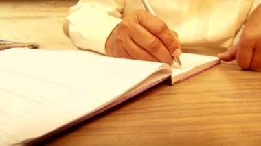 Yaşlı adam not defterine yazmak yukarıya kapatmak.