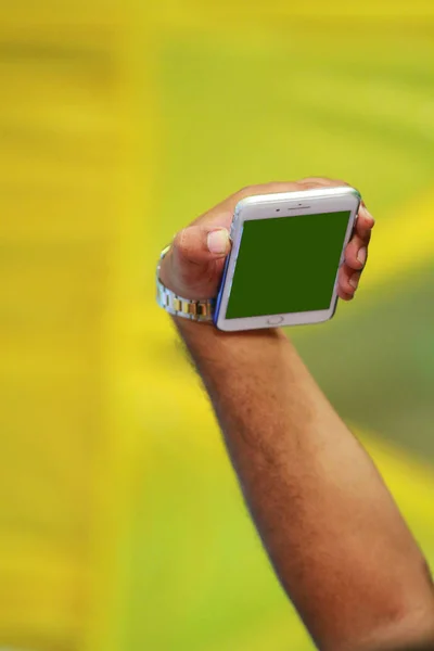 Mock up of male hand holding black cellphone at green background. — Stock Photo, Image