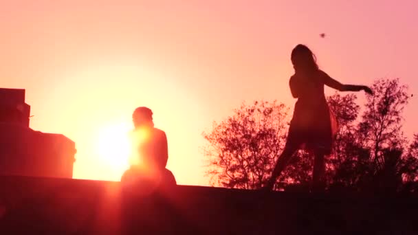 Pasangan bahagia menari di pantai menikmati bulan madu di alam saat matahari terbenam dengan bersiluet — Stok Video