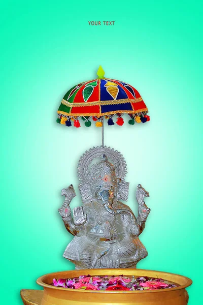 Silver statue of hindu god vinayagar and front of water bowl with flowers. blue background — Stock Photo, Image