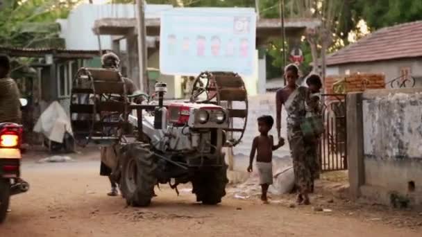 Indien - 28. März 2018: Bauer fährt roten alten Traktor zwischen landwirtschaftlichen Gebäuden und Geräten. — Stockvideo