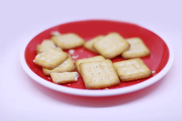 Στοίβα μπισκότων σε κόκκινο πιάτο σε λευκό φόντο. — Φωτογραφία Αρχείου