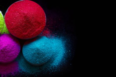 Koyu arkaplanda izole edilmiş kâselerdeki renkli holi tozunun üst görünümü.