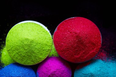 Koyu arkaplanda izole edilmiş kâselerdeki renkli holi tozunun üst görüntüsü. Mesaj için yer var. Mutlu bayramlar.