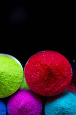 Koyu arkaplanda izole edilmiş kâselerdeki renkli holi tozunun üst görüntüsü