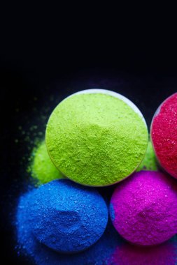 Koyu arkaplanda izole edilmiş kâselerdeki renkli holi tozunun üst görüntüsü