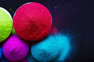 Koyu arkaplanda izole edilmiş kâselerdeki renkli holi tozunun üst görüntüsü. Mesaj için yer var. Mutlu bayramlar.