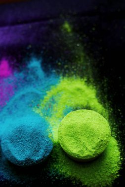 Koyu arkaplanda izole edilmiş kâselerdeki renkli geleneksel holi tozunun üst görünümü.
