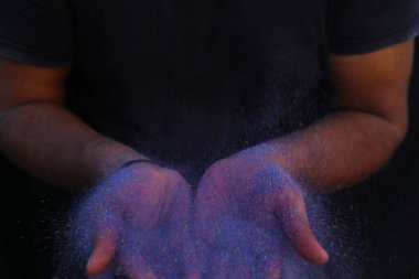 Canlı bir renk patlaması ile çevrili renkli holi tozunun el ele tutuşması.