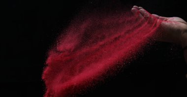 Kapalı el kırmızı renkli holi tozu siyah arkaplanlara sıçrıyor