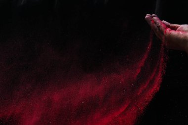 Kapalı el kırmızı renk holi tozu siyah arkaplanda sıçrıyor
