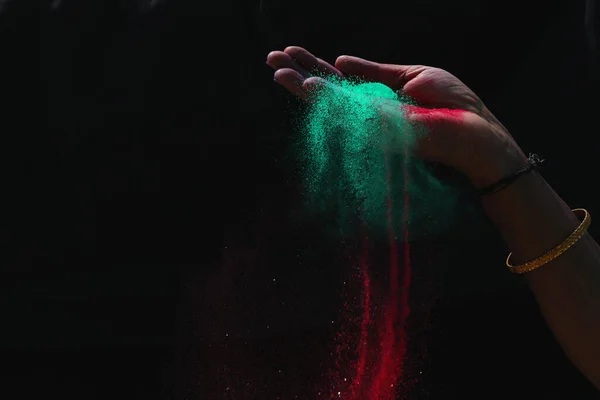Hintli kadın renkli holi tozu siyah arka planda sıçrıyor