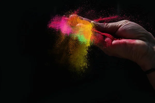 Indian woman hand colourful holi powder splash at black backgrounds