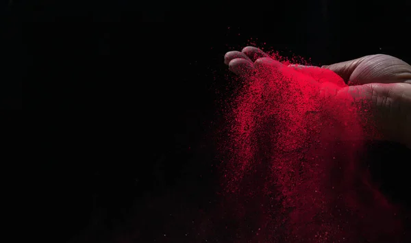 Kapalı el kırmızı renk holi tozu siyah arkaplanda sıçrıyor