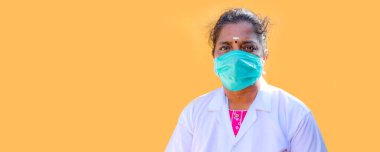 Sarı arka planda koruyucu maske takan kadın hemşire ya da doktor.