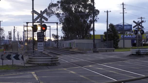 Железнодорожный переход с закрытием ворот, когда пригородный поезд метро проходит через железнодорожный переход в Австралии — стоковое видео