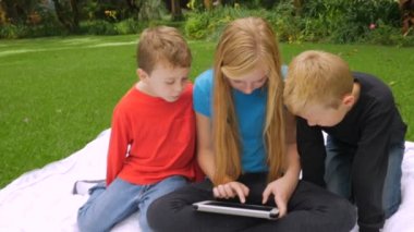 Üç çocuk bir tablet üzerinde oynarken bir sivrisinek - soketli swats vurdu