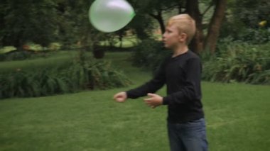 Bir balon ile oynarken mutlu sarışın genç bir çocuk kamera - slowmo görünüyor