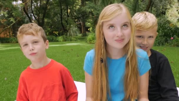 Drie kinderen kijken naar de camera en het geven van de duim naar beneden en lachen in slowmo — Stockvideo