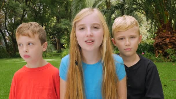 Três crianças pequenas olham para a câmera e brincam ao redor - slowmo — Vídeo de Stock