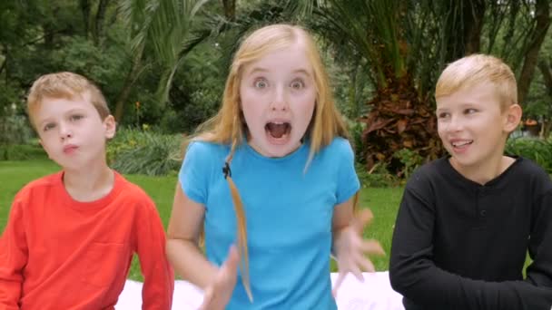 A young girl shows excitement and surprise while two boys imitates her — Stock video