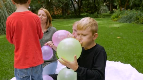 Una madre y sus tres hijos inflan globos juntos - slow mo — Vídeos de Stock