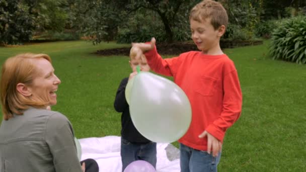 Un bambino guarda mentre il suo palloncino vola via mentre è seduto con la sua famiglia — Video Stock