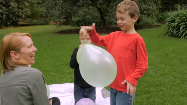 A little boy watches as his balloon flies away while sitting with his family — Stock Video