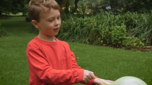 Um menino ruivo adorável brincando fora pausas para falar sobre algo - slowmo — Vídeo de Stock