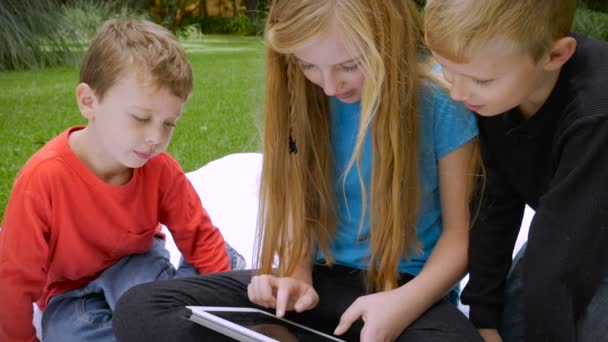 Three young children are completely engaged on their shared tablet - slowmo — Αρχείο Βίντεο