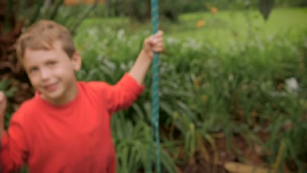 Um menino adorável balançando em um balanço lá fora em slowmo — Vídeo de Stock