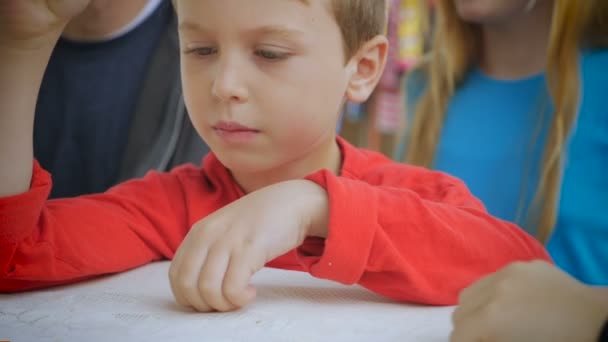 Un chico hace girar una peonza sobre una mesa con otro chico — Vídeos de Stock