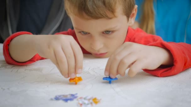 Хлопчик використовує обидві руки для обертання двох обертових вершин — стокове відео