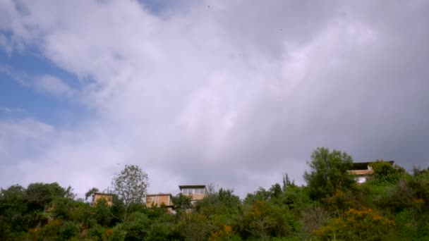 Bajo ángulo mirando hacia arriba a las casas en la ladera con destello de lente — Vídeos de Stock