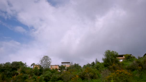 Upprätta skott av hus på bergssluttningen med fåglar som flyger i skyn — Stockvideo